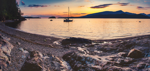 Wall Mural - Sailing and rocky sunset beaches in the pacific north west with a lighthouse guiding the way through the Salish sea to Vancouver British Columbia Canada.