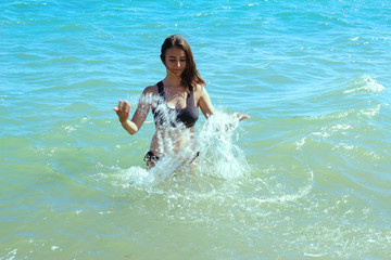 Wall Mural - brunette girl bathes in the sea, splashing water