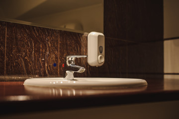 close up photo of a white oval sink and a steel faucet on a brown wooden table in the bathroom of a spa centre