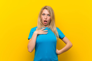 Poster - Young blonde woman over isolated yellow background surprised and shocked while looking right