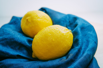 fresh lemon with water droplets above the blue cloth