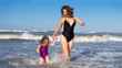 Happy beautiful model mother and daughter in swimsuits swimming in sea. Family lifestyle in ocean rest. Beautiful girls on sea vacation