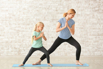 Mother with little girl doing yoga indoors