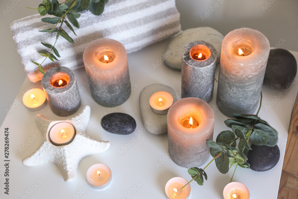 Beautiful burning candles with eucalyptus on table in room