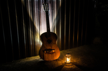 Wall Mural - An wooden acoustic guitar is against a grunge textured wall. The room is dark with a spotlight for your copyspace.