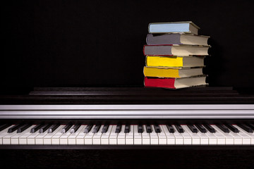 stack of colored books on the piano on a black background. Concept of education and reading.