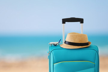 holidays. travel concept. blue suitcase and airplane toy infront of tropical sea background