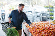 © Rob and Julia Campbell/Stocksy - 40's man choosing fruits and vegetables at the local grocery sto