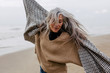 © Bonninstudio/Stocksy - Senior woman enjoying a winter day on the beach.