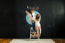 Two Girls Drawing Planet Earth On A Blackboard