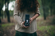 © Javier Pardina/Stocksy - woman with retro camera making pictures in the woods