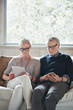 © Trinette Reed/Stocksy - Mature couple with grey hair looking at digital tablet and phone at home