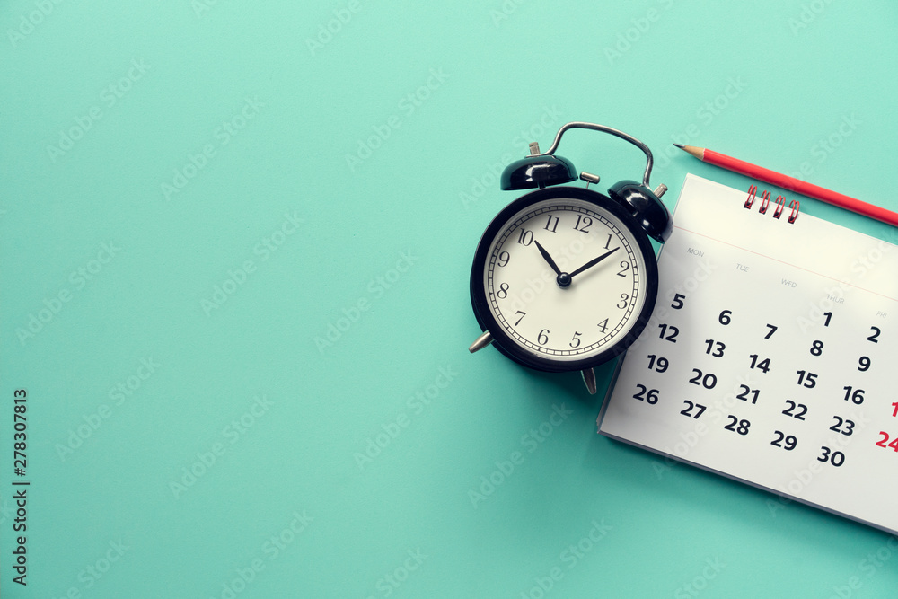 close up of calendar and alarm clock on the green background, planning for business meeting or travel planning concept - obrazy, fototapety, plakaty 
