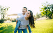 © My Ocean studio - Happy beautiful young mother is playing with her little son while he is riding on her back and shouting for joy.