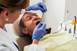 © Santi Nunez/Stocksy - Dentist during a dental intervention to senior man.