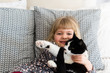 © L?a Jones/Stocksy - little blonde girl and her big black and white cat on a bed