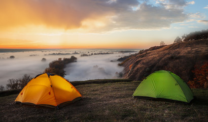 Wall Mural - orange and green tents over river sheltered by mist