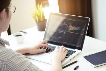 Young programmer is coding and developing software application in the software company office.