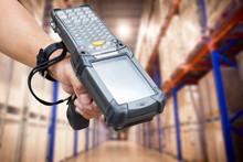 Close Up Hand Of Worker Holding Barcode Scanner With Warehouse Background.