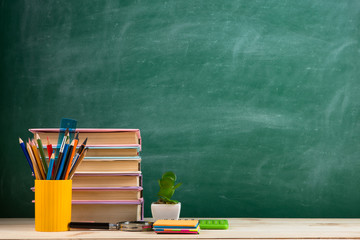 Education and reading concept - group of colorful books on the wooden table in the classroom, blackboard background