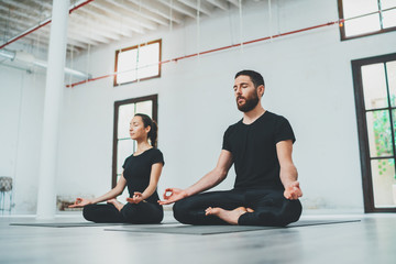 Yoga Practice Exercise Class Concept. Two beautiful people doing exercises.Young woman and man practicing yoga indoors