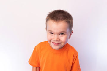 Little cute boy in a bright shirt, smiling, on a light background