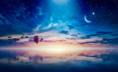 crescent and hot air balloon rising above serene sea in sunset glowing sky