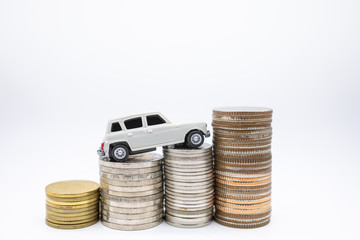 Close up of miniature toy card on top of stack of coins on white background with copy space.