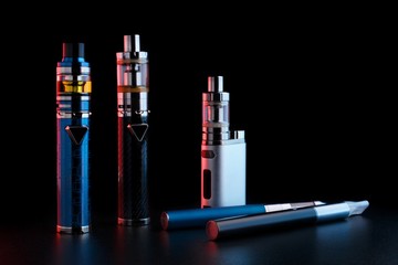 Wall Mural - electronic cigarettes or vaping devices on black background. Toned light