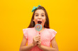 © Nexa - The child is holding a lollipop. Childish joy is sweetness. Little girl on yellow background.