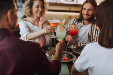 Good friends toasting with cocktails while spending time in cafe