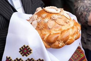 fresh bread with salt to hold in hands on a white embroidered towel. Russian wedding traditions. Delicious pie.