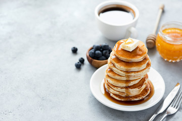 Wall Mural - Pancakes with butter, syrup and cup of coffee on concrete backdrop. Copy space for text. Classic American breakfast