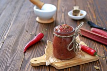 Spicy Rhubarb Chutney Sauce In A Glass Jar On A Wooden Background. Preserving, Harvesting. Indian Food.
