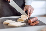 Fototapeta Kosmos - close up. man slicing cheese for sandwiches