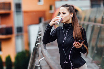 Morning concept.  Attractive woman after running holding coffee or tea and relaxing stay on stairs.