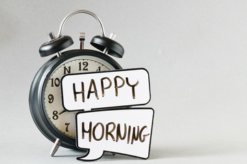 close-up view of retro alarm clock and speech bubbles with inscription happy morning on grey background