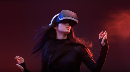 Wall Mural - beautiful woman with flowing hair in futuristic dress over dark background. girl in glasses of virtu