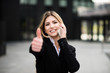 © Minerva Studio - Smiling business woman talking on the phone and thumbs up