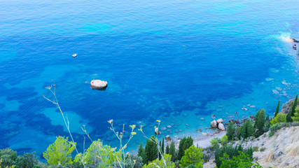 seascape view of a white rock in a blue and turquoise lagoon with two fisherman and a small boat in 