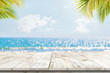 Leinwandbild Motiv Top of wood table with seascape and palm leaves, blur bokeh light of calm sea and sky at tropical beach background. Empty ready for your product display montage.  summer vacation background concept.