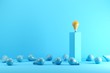 A Orange Light bulb stands on top of a pedestal surrounded by blue light bulbs on floor. Creative Idea concept. 3d render.