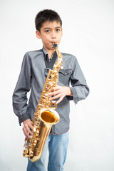 Little asian musician boy playing saxophone instrument