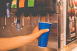 hand holding a paper glass to pour the lemonade soda soft drink  machine  in a fastfood restaurant