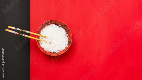 Fotomural High angle view of white vermicelli in bowl with chopsticks over dual backdrop