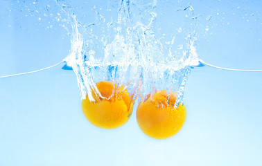 Two ripe oranges falling deeply under water with big splash