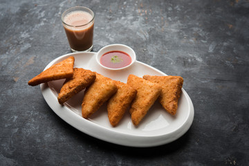 Poster - crispy Potato triangles or batata vada covered with bread crumbs and then deep fried. served with tomato ketchup. selective focus