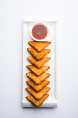 Poster - crispy Potato triangles or batata vada covered with bread crumbs and then deep fried. served with tomato ketchup. selective focus