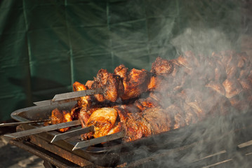 Barbecue fries in the coals. Meat and beef at the field kitchen festival. Fried meat on an iron tray on the table.