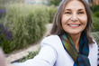 © shurkin_son - Summertime, people, age and leisure concept. Close up of beautiful blue eyed mature European lady in elegant clothes enjoying nice summer day outdoors, taking selfie using cell phone, smiling happily